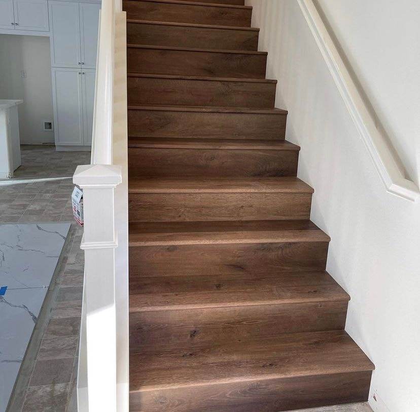 Escalera con peldaños de madera oscura y contrahuellas blancas en una casa