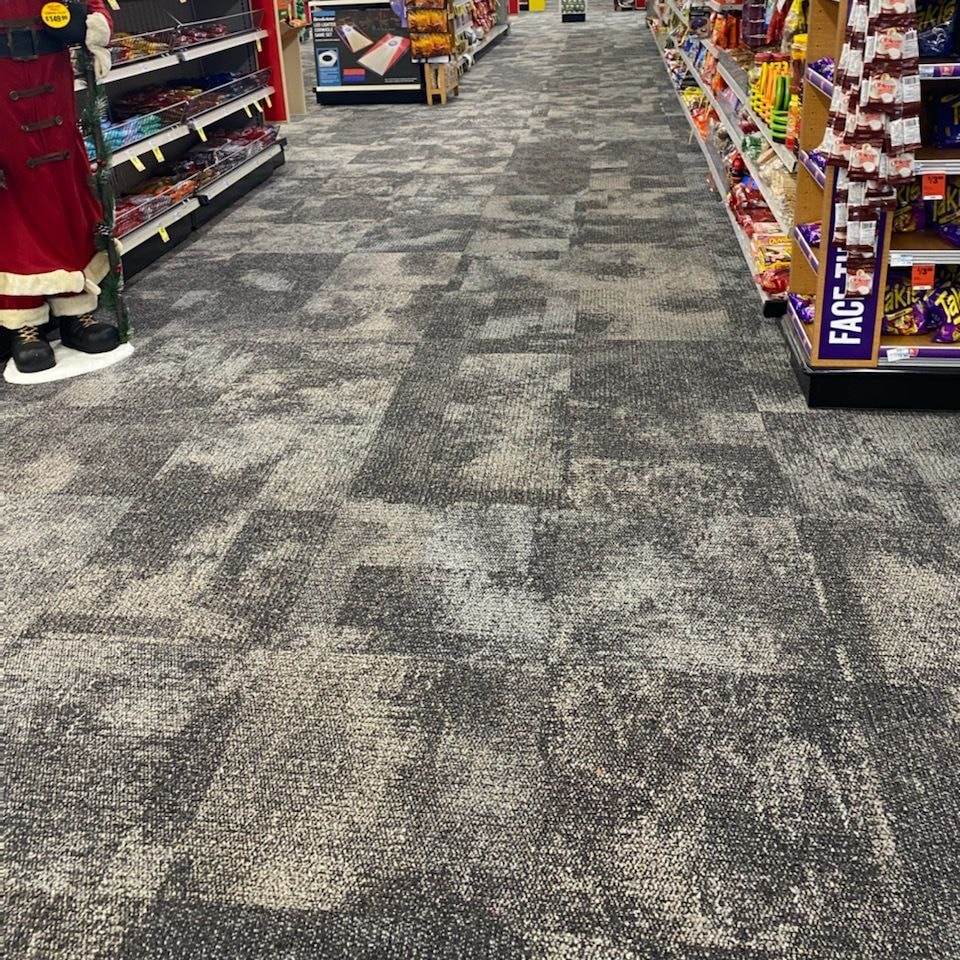 Pasillo de una tienda con piso de losetas de alfombra gris