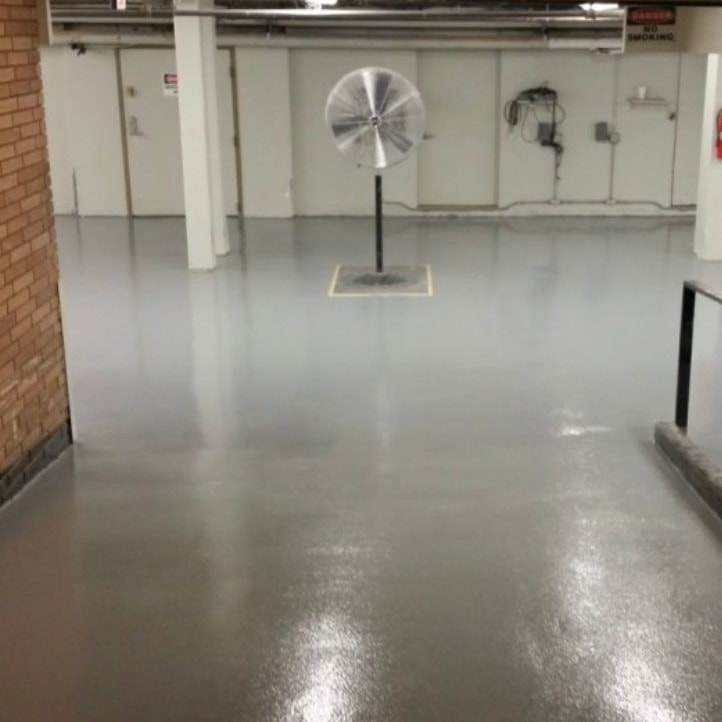 Piso epóxico gris en un edificio industrial, con un ventilador de pie